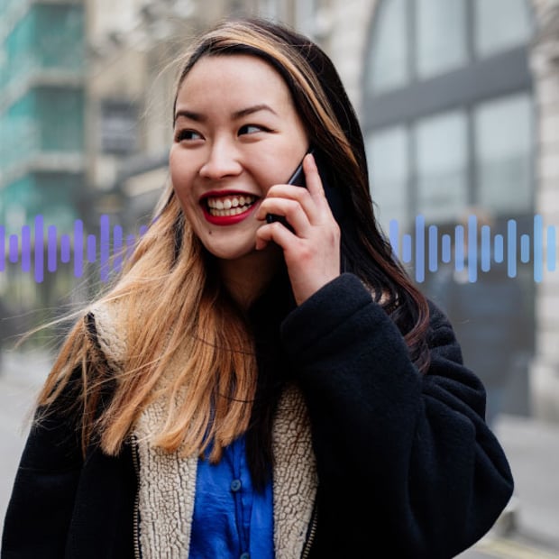 Photo of a smiling woman on a city street talking on her cell phone